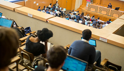 Image of a lecture hall with a professor and students.